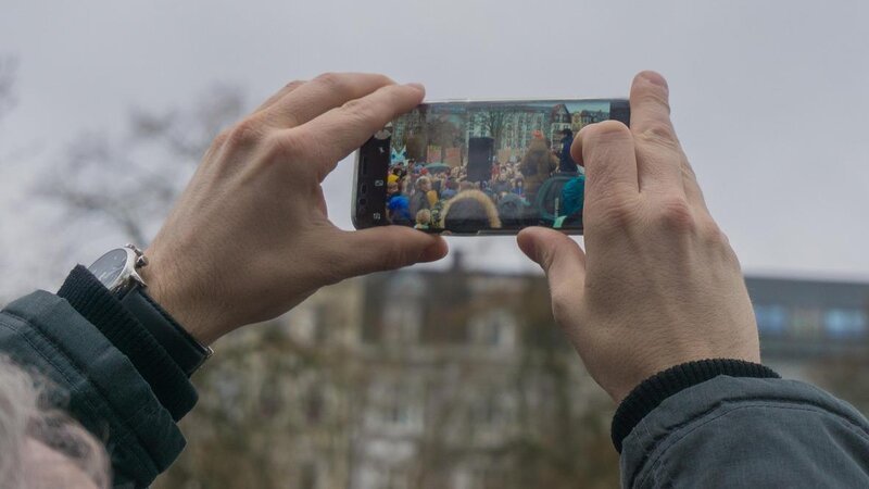 Eine Person filmt eine Demonstration mit dem Handy.