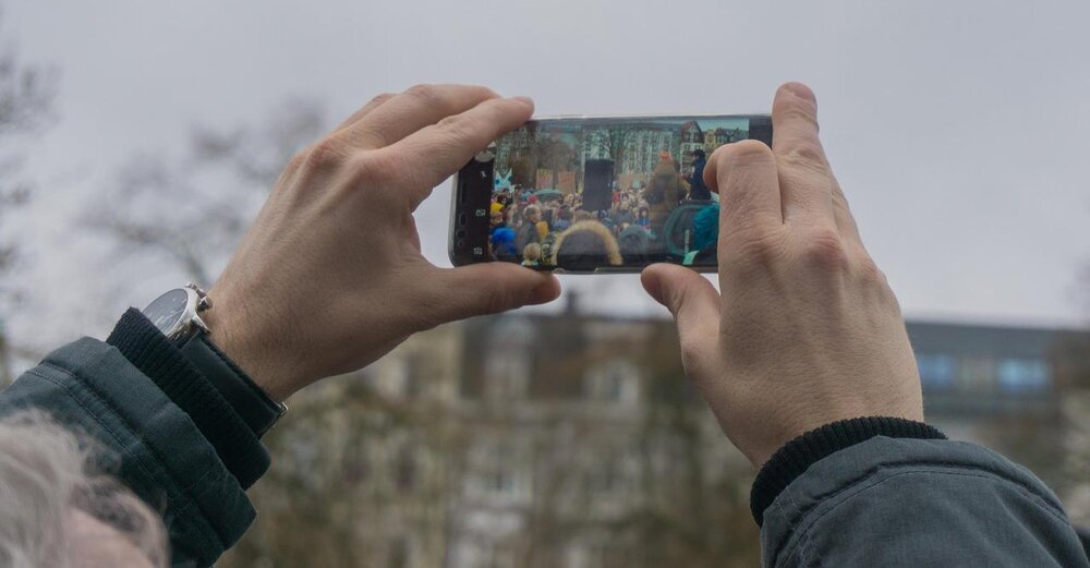 Eine Person filmt eine Demonstration mit dem Handy.