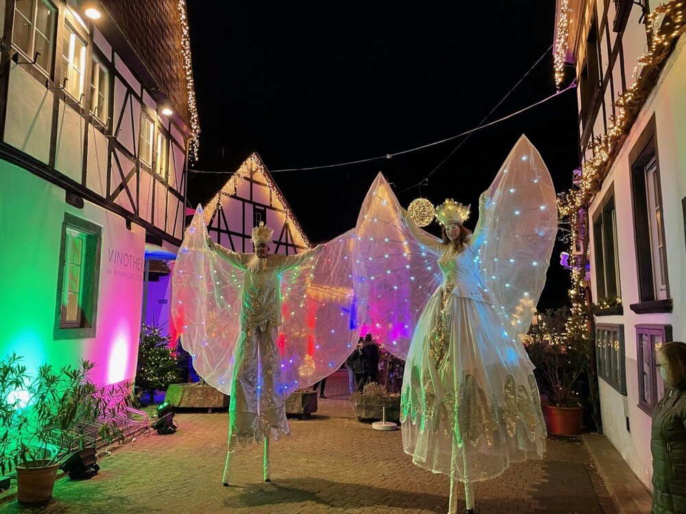 Elegant kostümierte und beleuchtete Stelzenläufer bei Winningen im Lichterglanz.