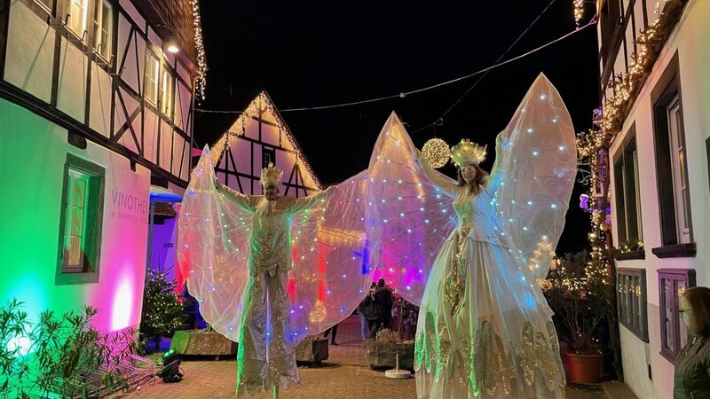 Elegant kostümierte und beleuchtete Stelzenläufer bei Winningen im Lichterglanz.