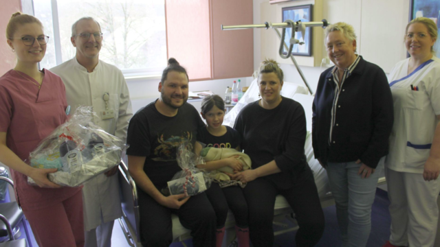 Das Foto zeigt die stolzen Eltern ihre Tochter Maya flankierend, die ihren Bruder im Arm hält, sowie stehend v.l. Hebamme Sophie Urmersbach, Oberarzt Dr. med. Sebastian Friederichs, Bürgermei Erster Schängel 2026 im Koblenzer Kemperhof geboren