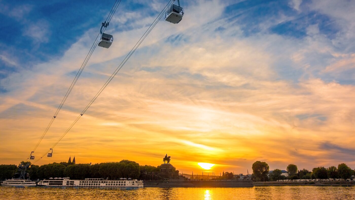 Abendhimmel in Koblenz, die Sonne geht unter, die Seilbahn fährt und das Deutsche Eck sowie der Rhein sind in Sichtweite