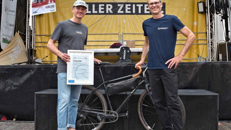 Glücksbringer Tom Steffens (links im Bild) zog die Lose bei der Abschlussveranstaltung. Er schaffte mit 2.328 km beim STADTRADELN die meisten Kilometer und wurde für diese Leistung von Ralph 