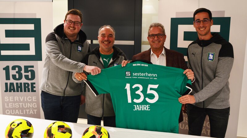 Die Vorstandmitglieder Max Jacobs (links), Wolfgang Knöll (2. von links) und Niclas Kuhn (rechts) brachten Johannes Sesterhenn (2. von rechts) zur Auslosung ein SG-Trikot zum 135-Jährigen Jub