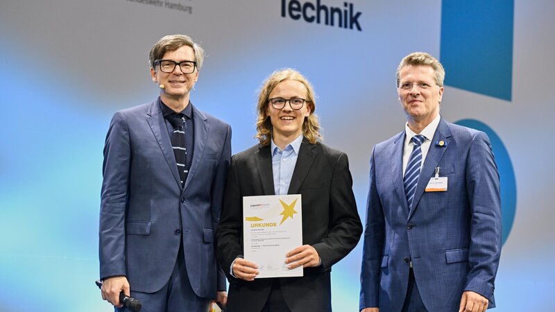 Jonathan Baschek (Mitte) erhielt die Urkunde aus den Händen von Professor Lutz Eckstein (rechts). Links: Moderator Ralf Caspers