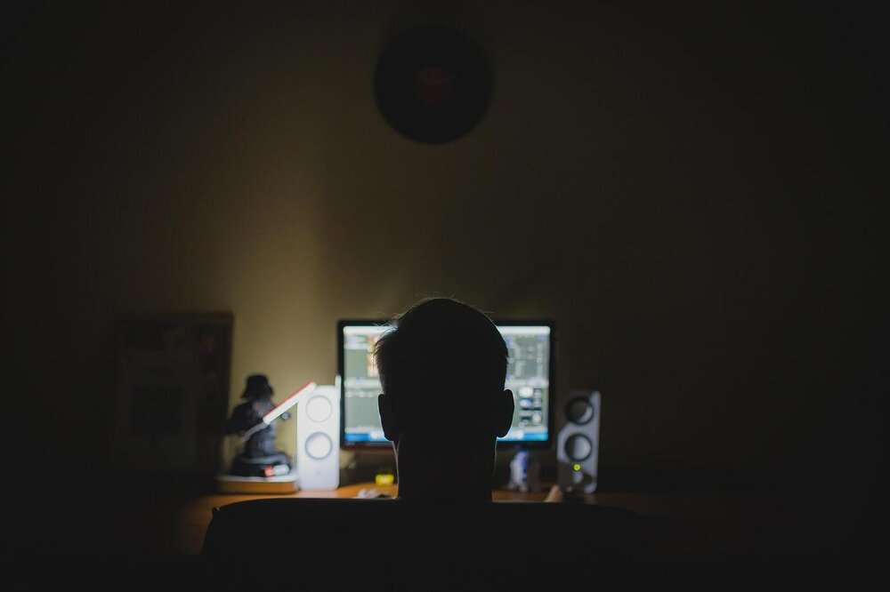 Ein Mann sitzt vor einem PC in einem dunklen Raum, Symbolbild. Ein Mann sitzt vor einem PC in einem dunklen Raum, Symbolbild.