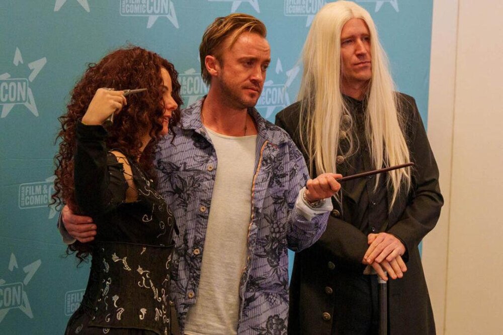 Harry Potter Star Tom Felton macht ein Foto mit zwei Fans.