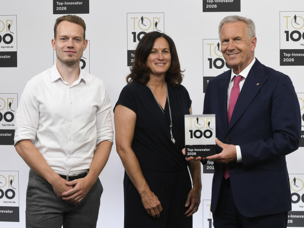 Große Freude beim Innovationsteam der evm: Christian Wulff überreicht Julia Holly und Janos Justen von der evm den Top 100-Award.