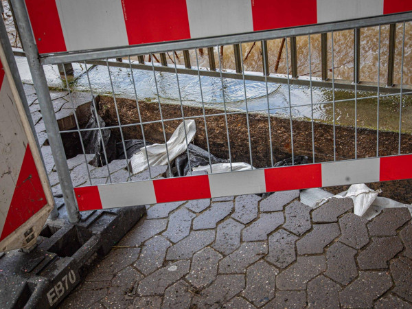 Im Gehweg am Peter-Altmeier-Ufer in Koblenz klafft ein Loch, das in Richtung Mosel provisorisch mit Sandsäcken abgedichtet wurde.