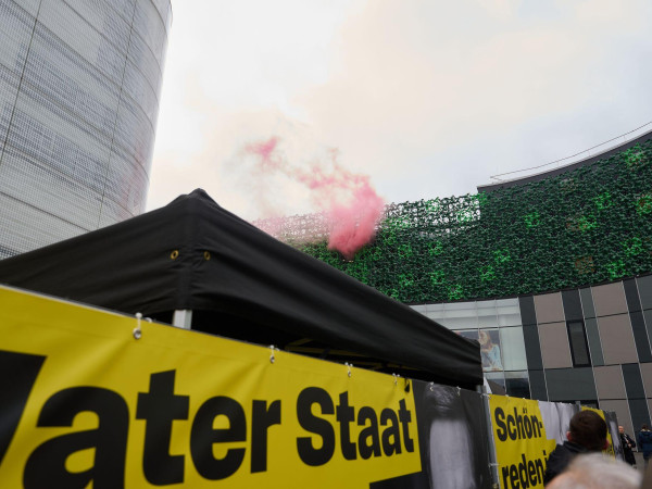 Protestierende haben während der Rede rosa Rauch von einem Dach aufsteigen lassen.